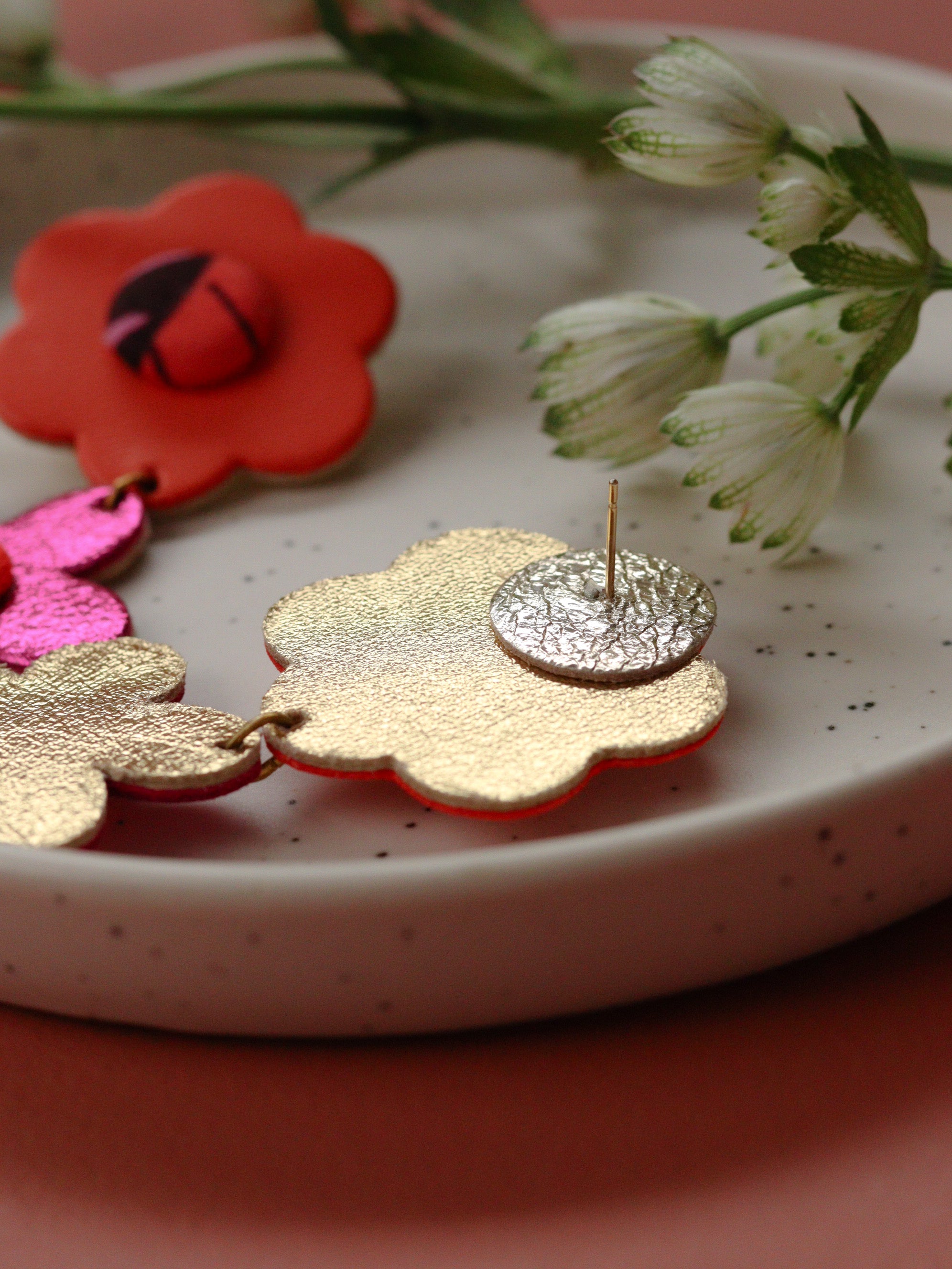 Détail puce boucles d’oreilles deux fleurs en cuir orange et rose et tissu wax, fabrication artisanale, couleurs pop