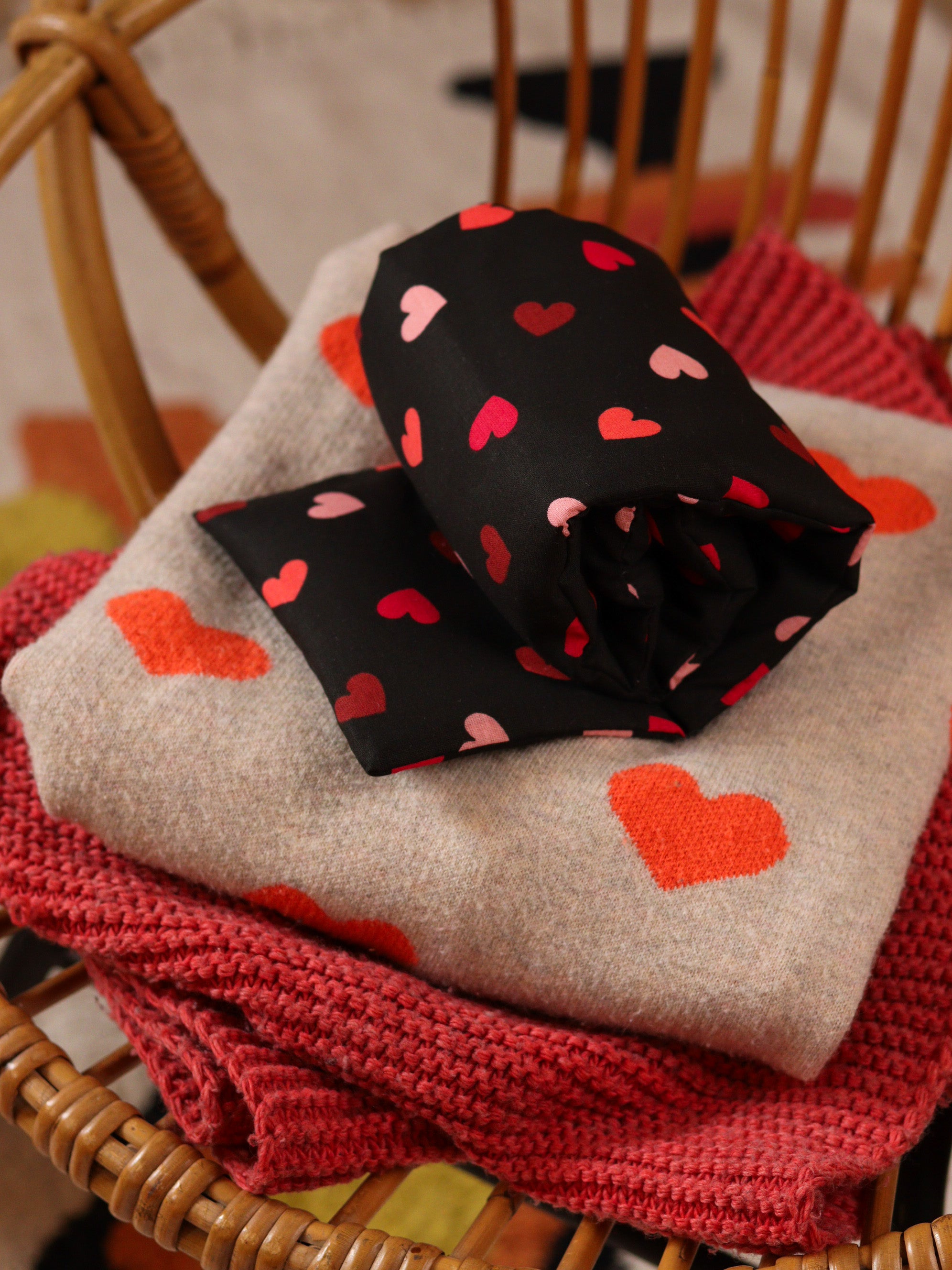 bouillotte longue aux graines de lin bio pour se détendre, apaiser l'esprit et réduire l'anxiété, joli tissu noir avec des cœurs, fabrication française