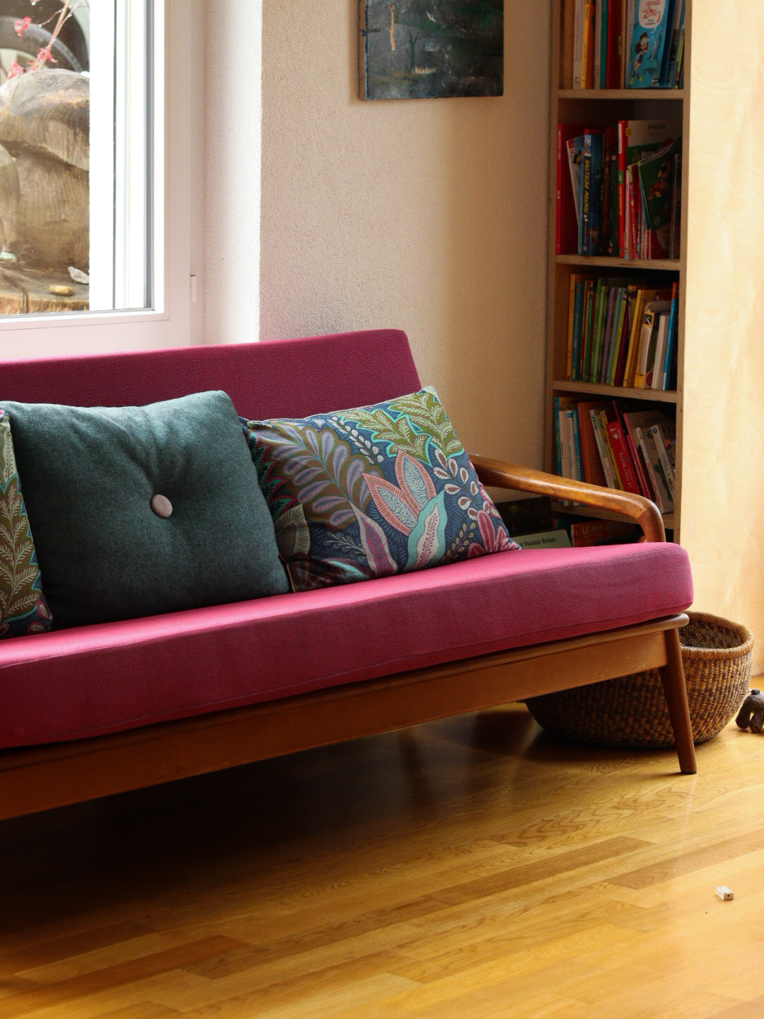 coussins personnalisés bleu avec motif végétal et passepoil coloré, canapé vintage bois et tissu rose framboise