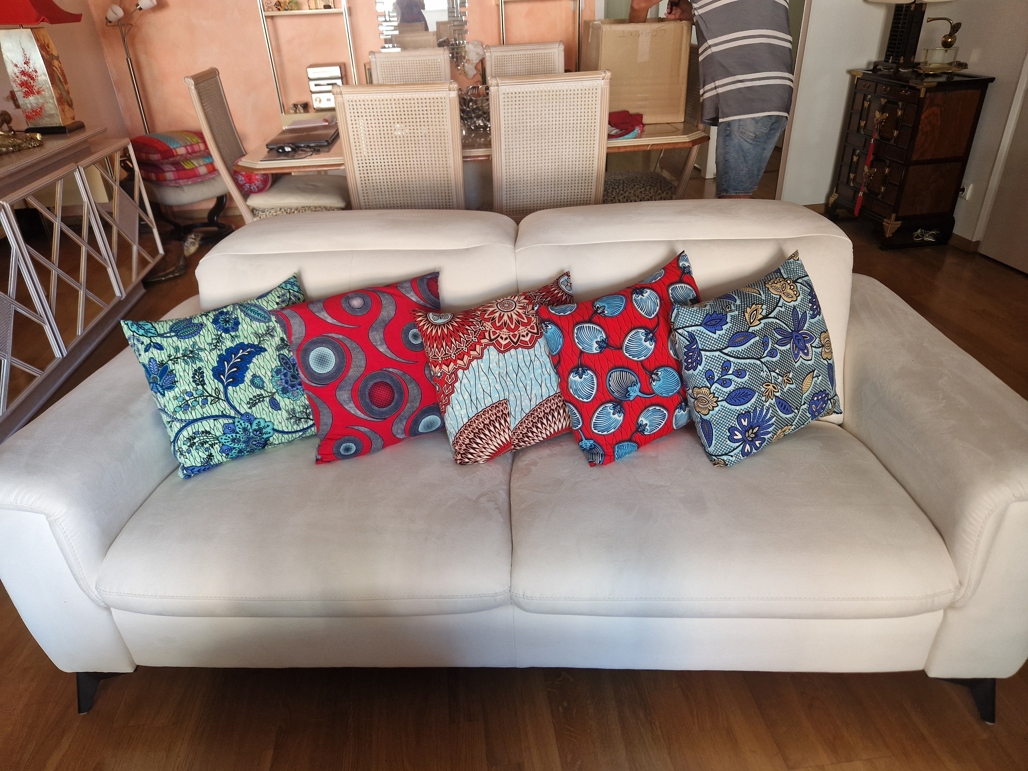 Mise en scène de coussins en wax bleu et rouge dans un salon.