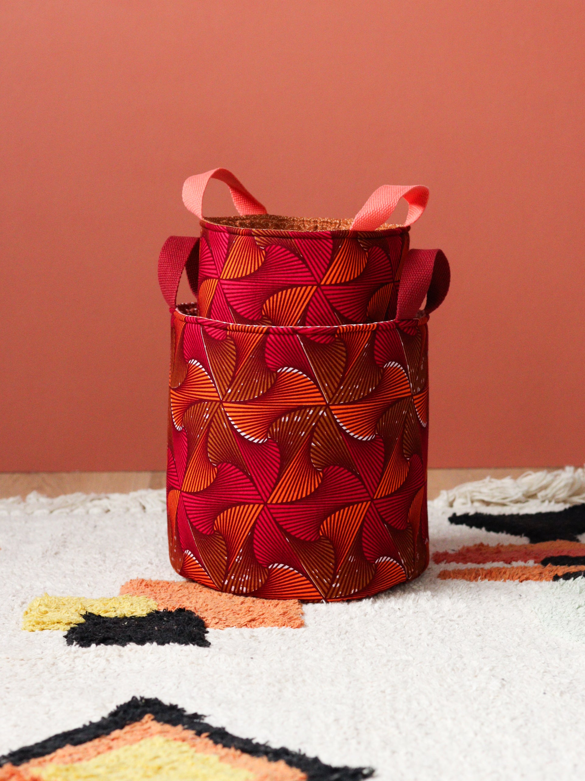 Duo de paniers wax africain orange rose posés dans un salon coloré