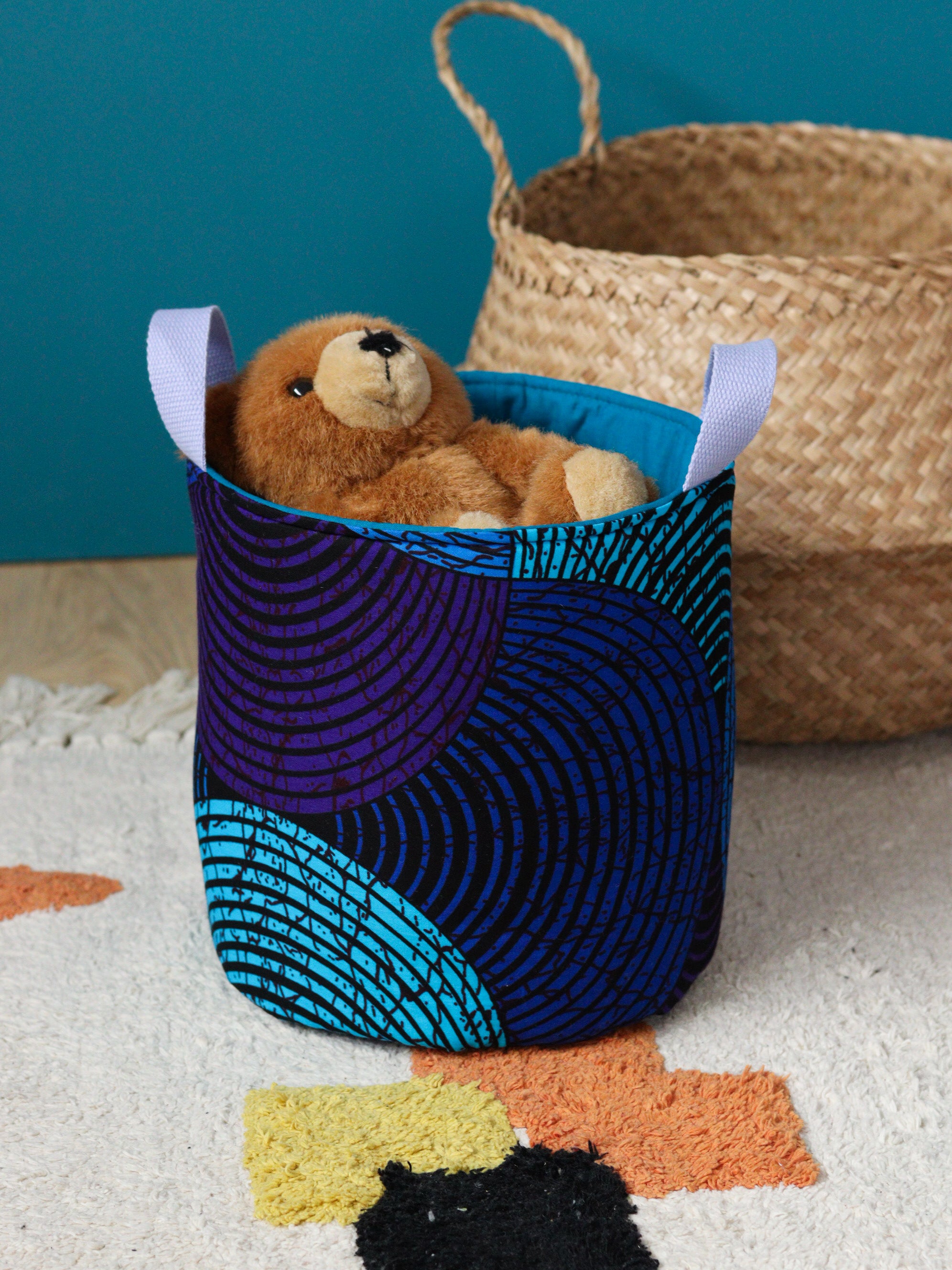 Panier déco Ondes bleues posé dans une chambre enfant colorée avec jouets et doudous