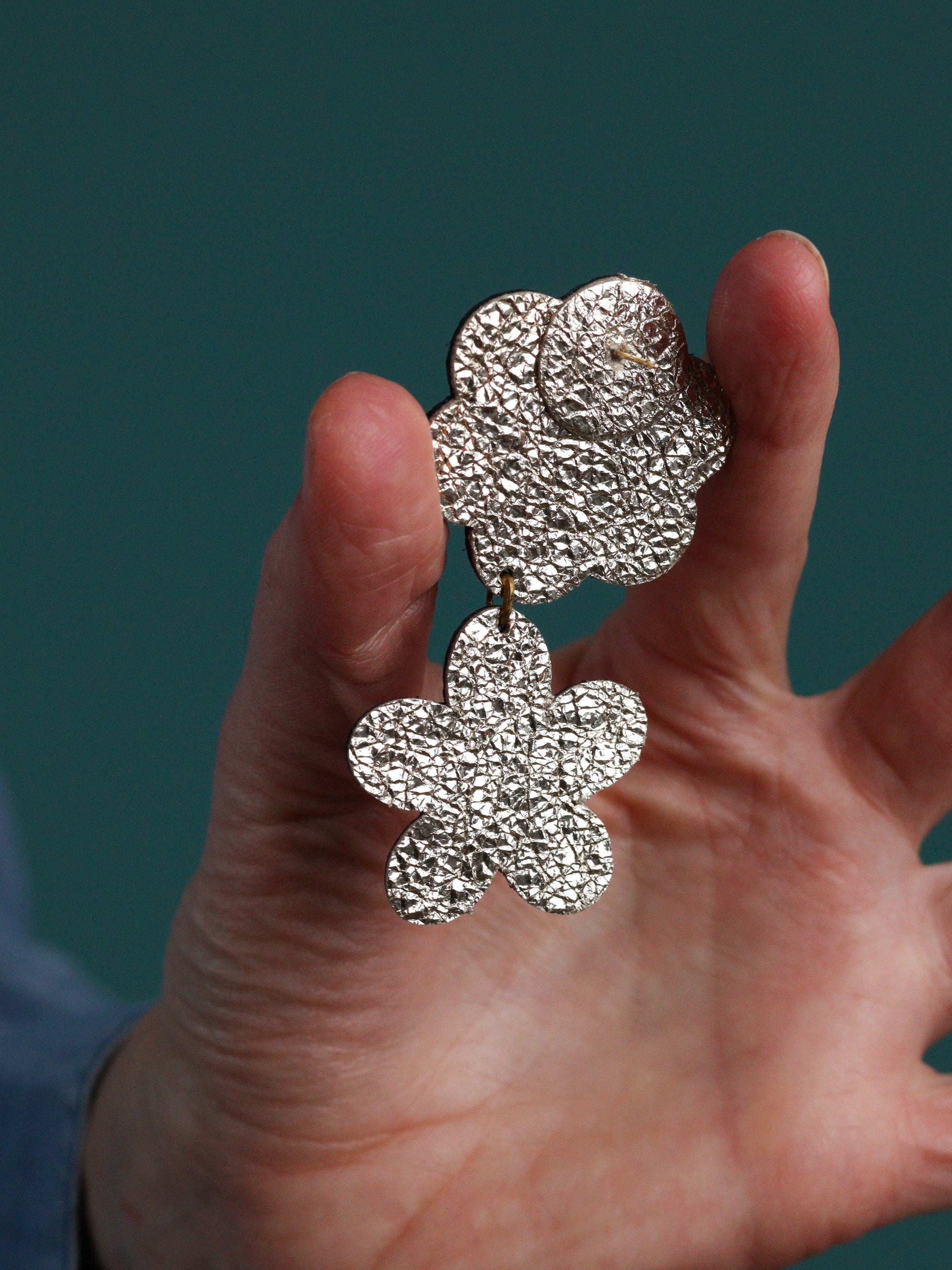 Détail boucles d’oreilles deux fleurs en cuir vert et tissu wax, fabrication artisanale, style jungle exotique