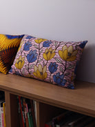 coussin wax violet à fleurs jaunes, posé sur banquette