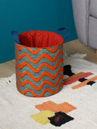 Panier déco L wax africain chevrons orange vif sur fond bleu crème, posé au sol