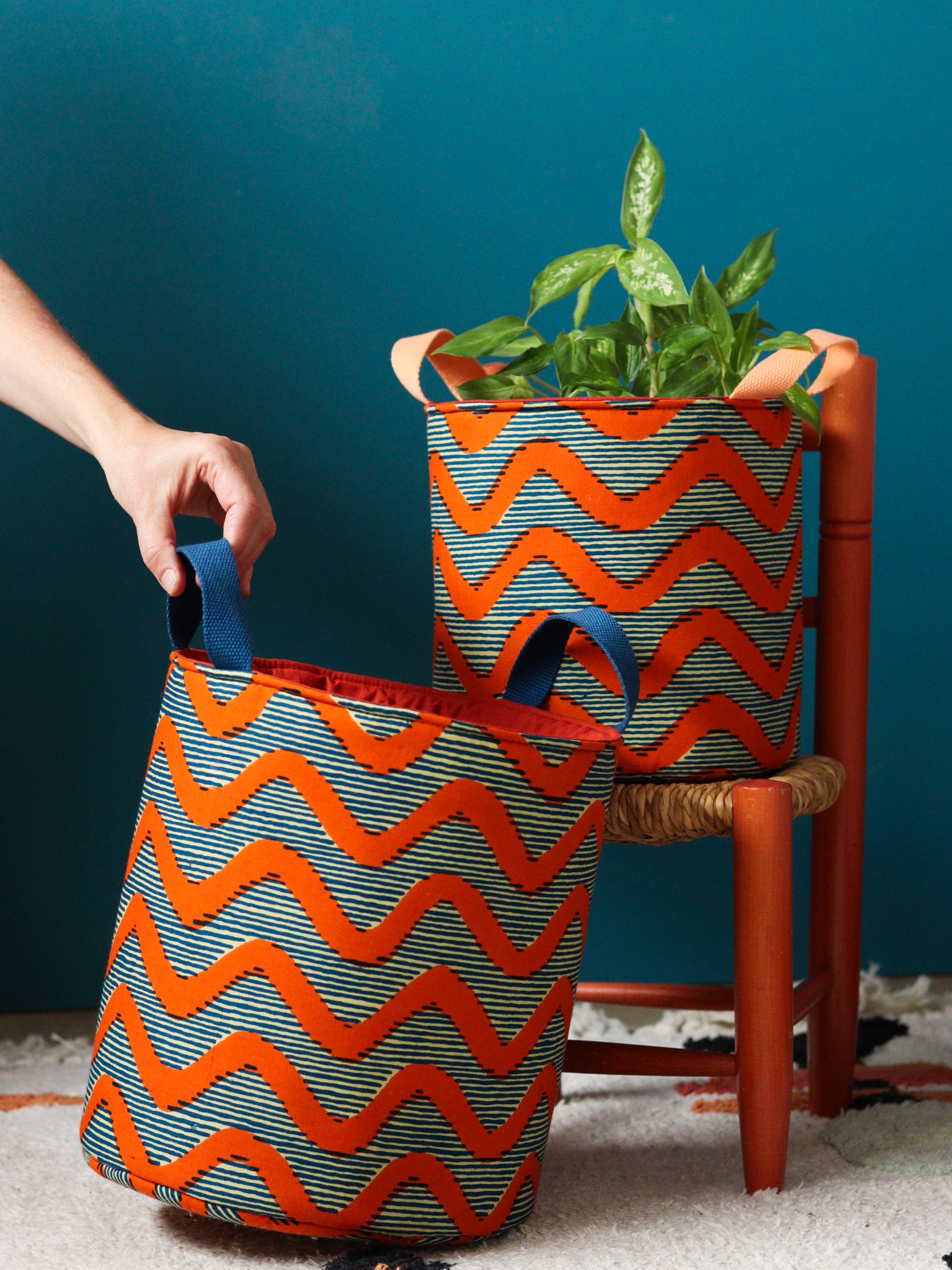 Panier déco coloré en wax africain motif zigzag orange, utilisé en cache-pot avec plante verte