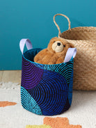 Panier déco Ondes bleues posé dans une chambre enfant avec jouets et doudous
