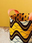 Détail anses panier déco S wax Savane posé sur un tapis, rangement coloré